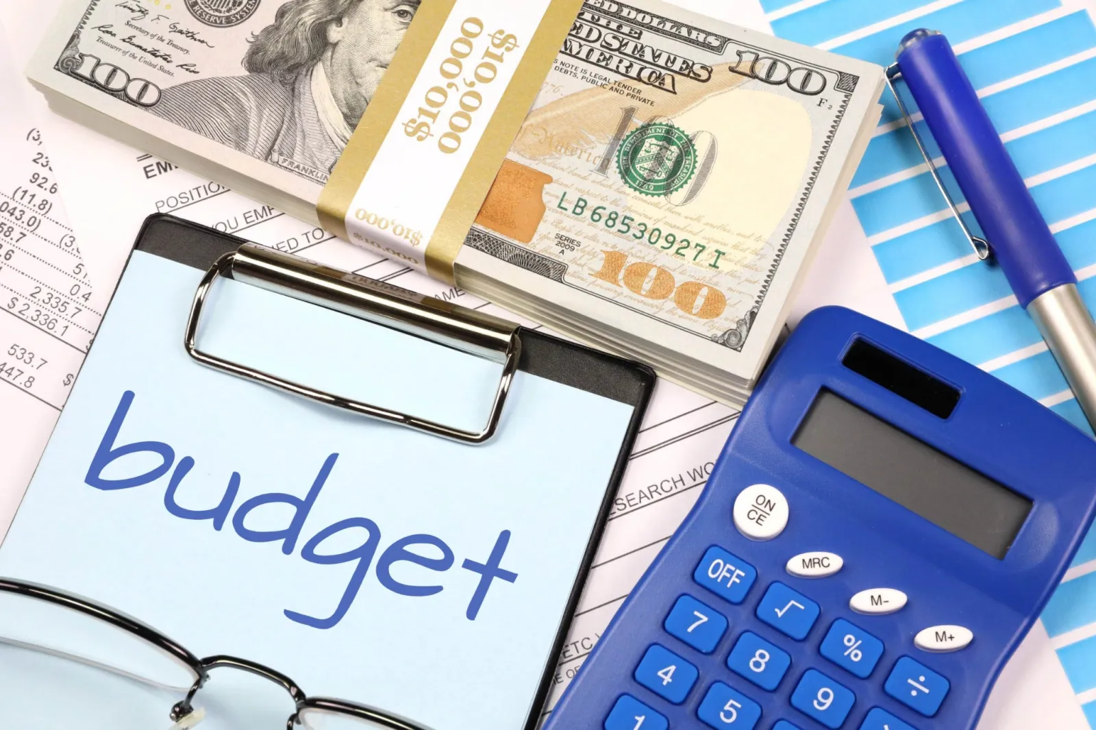 Clipboard with the word budget next to cash, a calculator and a pen